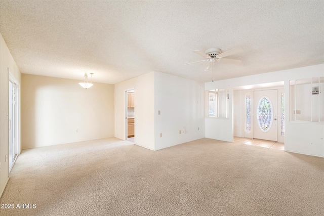 unfurnished living room with ceiling fan, a textured ceiling, and light colored carpet