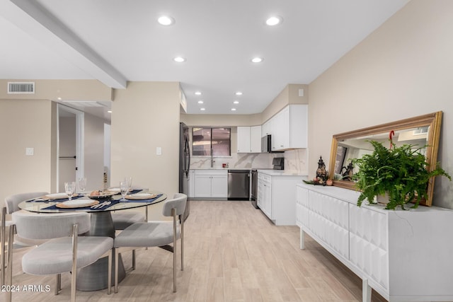 kitchen with appliances with stainless steel finishes, light wood-type flooring, white cabinets, decorative backsplash, and beam ceiling