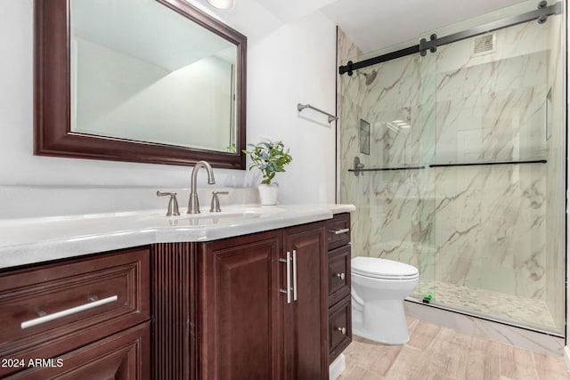 bathroom featuring vanity, wood-type flooring, a shower with door, and toilet