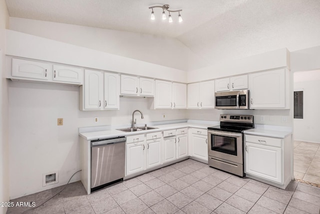 kitchen featuring white cabinets, lofted ceiling, stainless steel appliances, and a sink