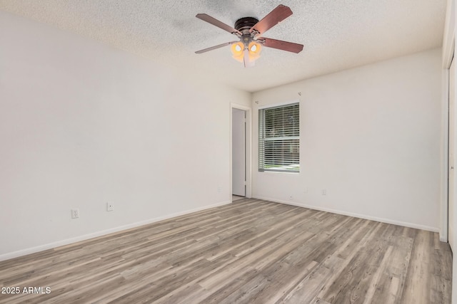 unfurnished room with light wood-style flooring, a textured ceiling, a ceiling fan, and baseboards