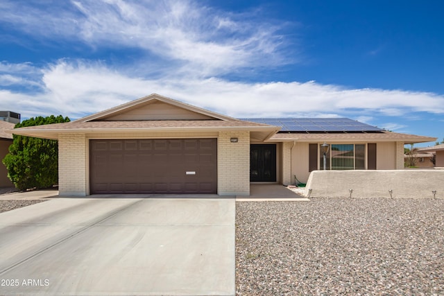 single story home with a garage and solar panels