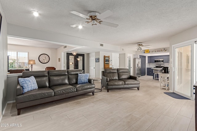 living room with a textured ceiling and ceiling fan