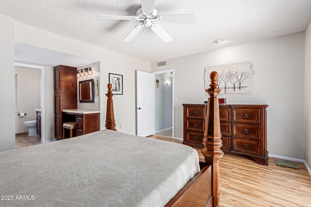 bedroom featuring light hardwood / wood-style flooring, a textured ceiling, ensuite bath, and ceiling fan