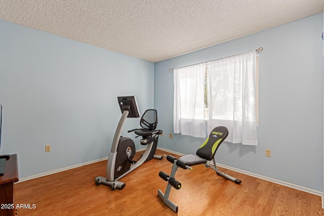 exercise area featuring wood-type flooring and a textured ceiling