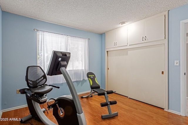 workout area featuring light hardwood / wood-style flooring and a textured ceiling