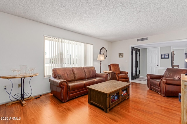 living room with a textured ceiling and light hardwood / wood-style flooring