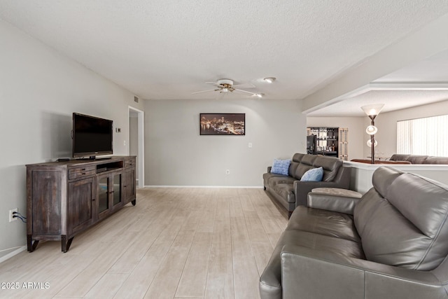 living room featuring ceiling fan, a textured ceiling, and light hardwood / wood-style floors