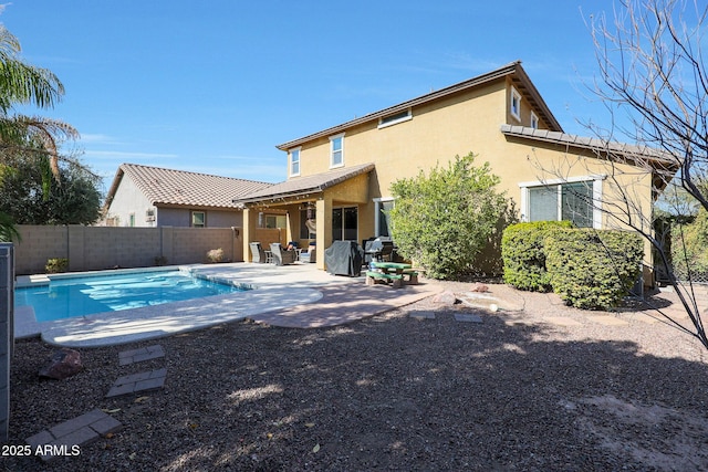 rear view of property featuring a fenced in pool and a patio area