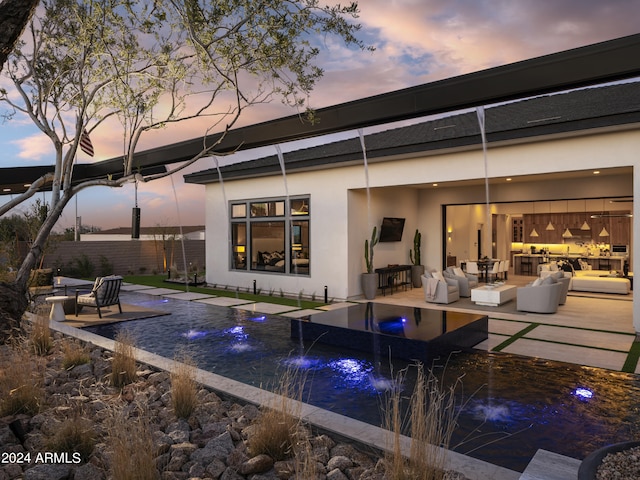 back house at dusk featuring a fenced in pool, outdoor lounge area, a patio, and pool water feature