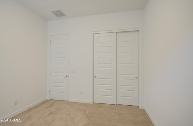 unfurnished bedroom featuring light colored carpet and a closet