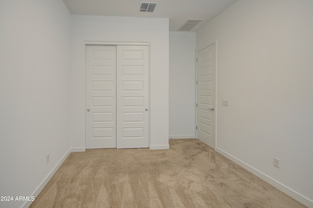 unfurnished bedroom with light carpet and a closet