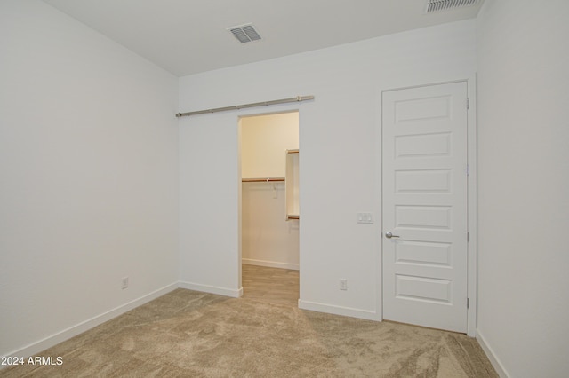 2228 E Isaiah Ave, Gilbert, AZ 85298 - unfurnished bedroom featuring light carpet, a walk in closet, baseboards, and a closet