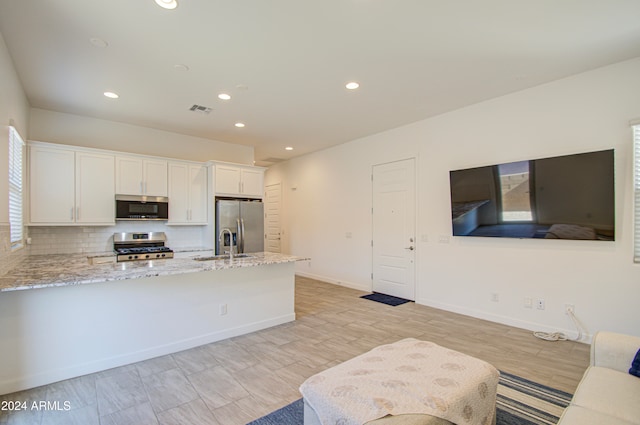 kitchen featuring white cabinets, decorative backsplash, light stone counters, kitchen peninsula, and stainless steel appliances