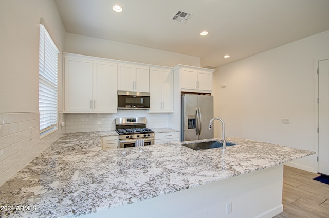 kitchen featuring sink, light hardwood / wood-style flooring, decorative backsplash, white cabinetry, and stainless steel appliances