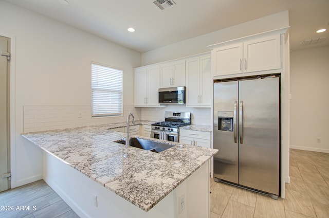 kitchen featuring light stone countertops, sink, stainless steel appliances, kitchen peninsula, and white cabinets