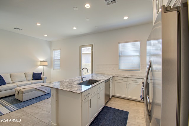 kitchen with light stone countertops, sink, kitchen peninsula, white cabinets, and appliances with stainless steel finishes