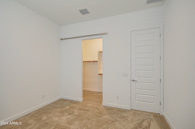 unfurnished bedroom with light carpet, a spacious closet, and a closet