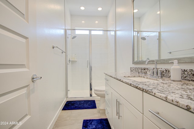 bathroom featuring tile patterned floors, vanity, toilet, and a shower with door