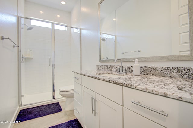 bathroom featuring tile patterned floors, vanity, toilet, and a shower with shower door