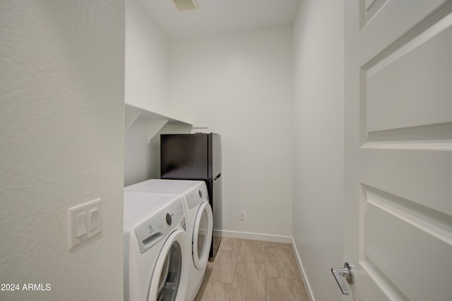 laundry room featuring washer and clothes dryer and light wood-type flooring