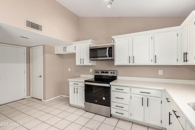 kitchen featuring visible vents, lofted ceiling, stainless steel appliances, light countertops, and white cabinets