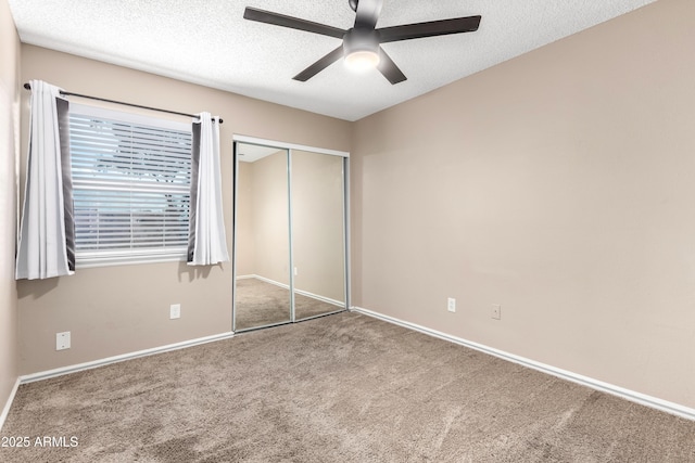 unfurnished bedroom with carpet, baseboards, a closet, and a textured ceiling