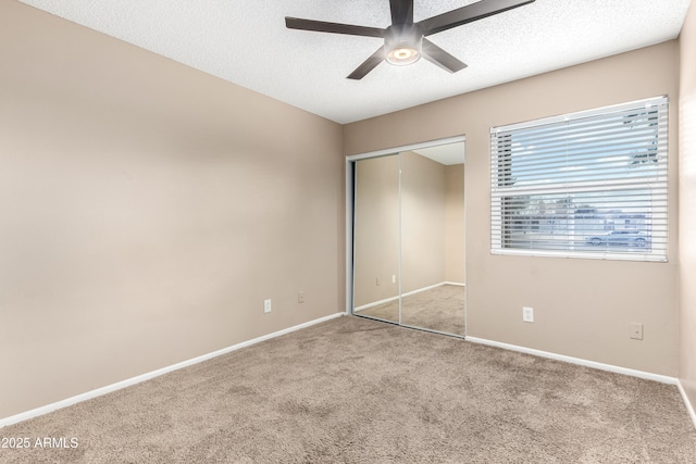 unfurnished bedroom featuring a closet, a textured ceiling, baseboards, and carpet floors