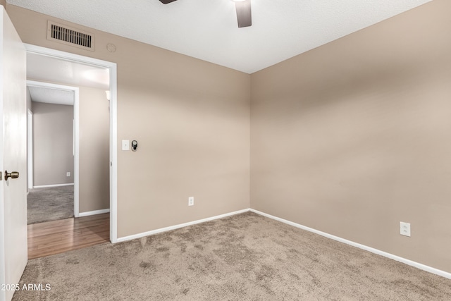 unfurnished room featuring baseboards, visible vents, a ceiling fan, and carpet