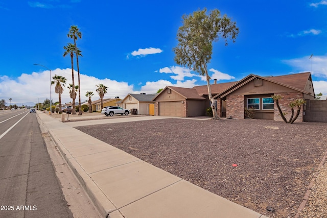 view of front of home with an attached garage, a residential view, brick siding, and driveway