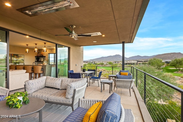 view of patio with an outdoor hangout area, exterior bar, a mountain view, and ceiling fan