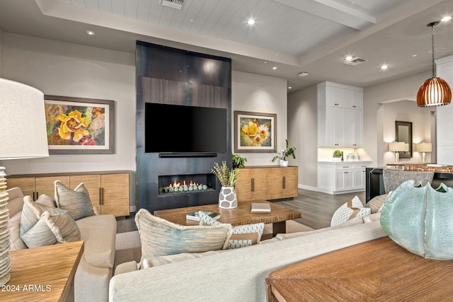 living room featuring beamed ceiling, a large fireplace, and dark hardwood / wood-style floors