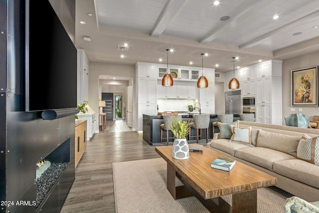 living room featuring sink, wood-type flooring, and beam ceiling