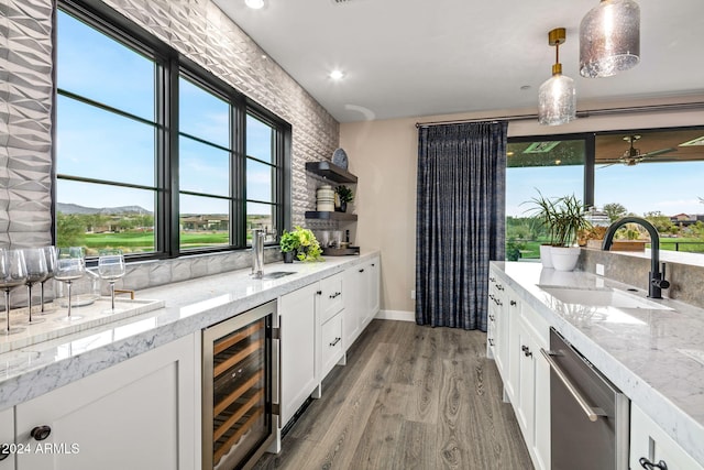 bar featuring beverage cooler, dishwasher, hardwood / wood-style floors, hanging light fixtures, and sink