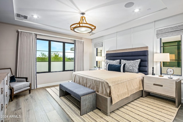 bedroom with a raised ceiling and light hardwood / wood-style flooring