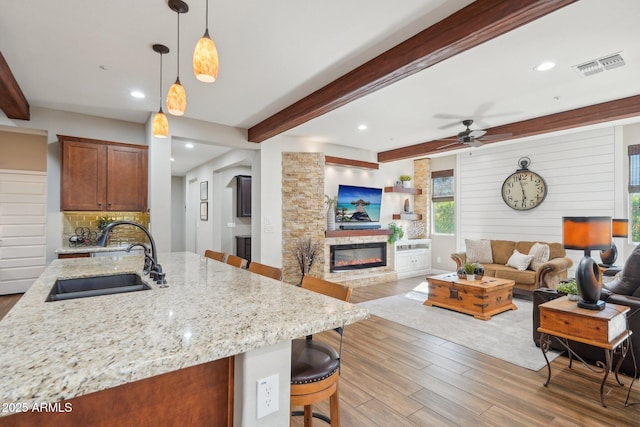 30342 N 130th Dr, Peoria, AZ 85383 - kitchen with a sink, visible vents, a ceiling fan, a glass covered fireplace, and wood finished floors