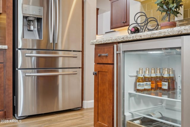 30342 N 130th Dr, Peoria, AZ 85383 - kitchen with light wood finished floors, refrigerator, light stone counters, stainless steel fridge with ice dispenser, and backsplash