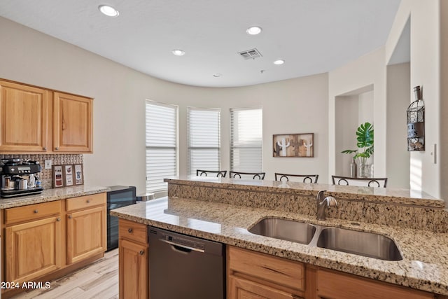 kitchen featuring tasteful backsplash, light wood-type flooring, light stone countertops, sink, and dishwasher