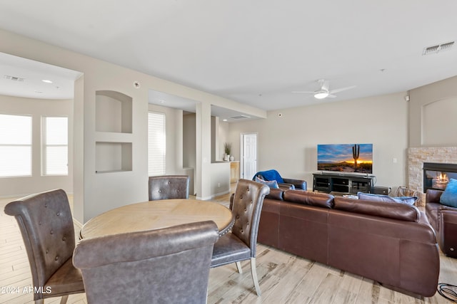 living room featuring a fireplace, light hardwood / wood-style floors, and ceiling fan