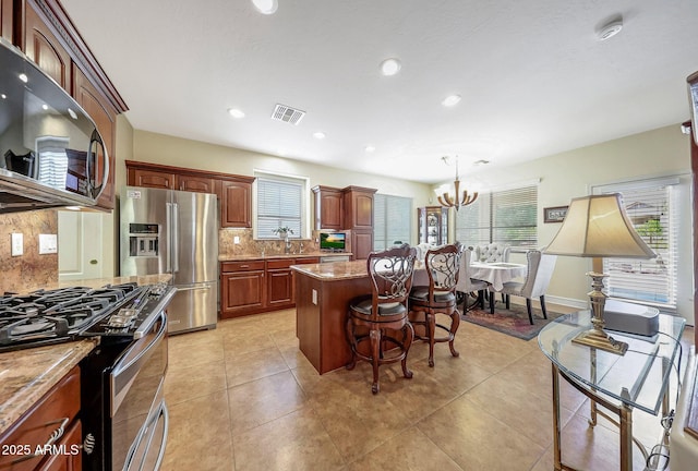 2726 S 160th Ave, Goodyear, AZ 85338 - kitchen with appliances with stainless steel finishes, backsplash, a kitchen island, a chandelier, and a breakfast bar area
