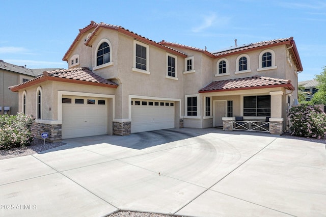 2726 S 160th Ave, Goodyear, AZ 85338 - mediterranean / spanish-style home with stone siding, an attached garage, a tile roof, and roof mounted solar panels