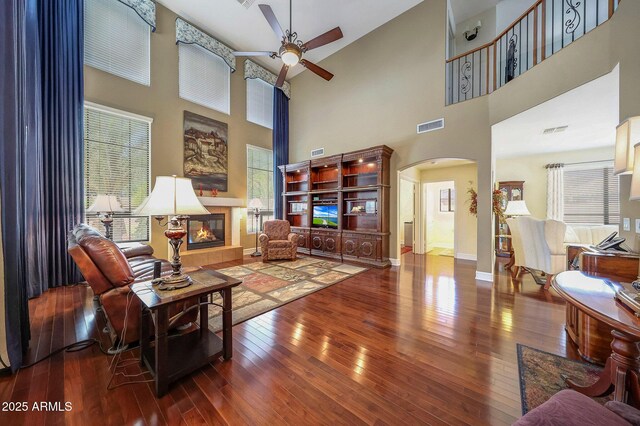 2726 S 160th Ave, Goodyear, AZ 85338 - living area with arched walkways, ceiling fan, a tiled fireplace, hardwood / wood-style flooring, and high vaulted ceiling