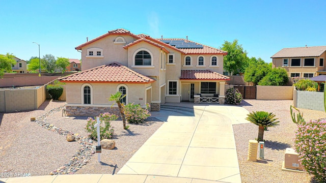 2726 S 160th Ave, Goodyear, AZ 85338 - mediterranean / spanish-style home with stucco siding, solar panels, a tiled roof, and fence
