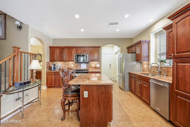 2726 S 160th Ave, Goodyear, AZ 85338 - kitchen with appliances with stainless steel finishes, a sink, arched walkways, a kitchen island, and recessed lighting