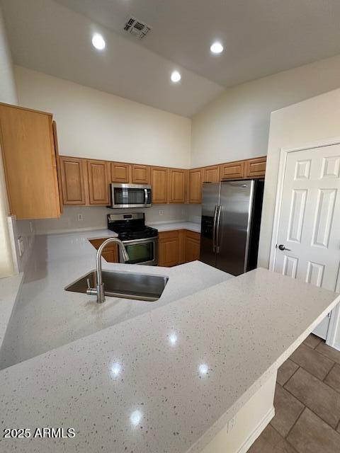 20275 N 81st Ln, Peoria, AZ 85382 - kitchen featuring stainless steel appliances, a sink, a peninsula, high vaulted ceiling, and brown cabinetry