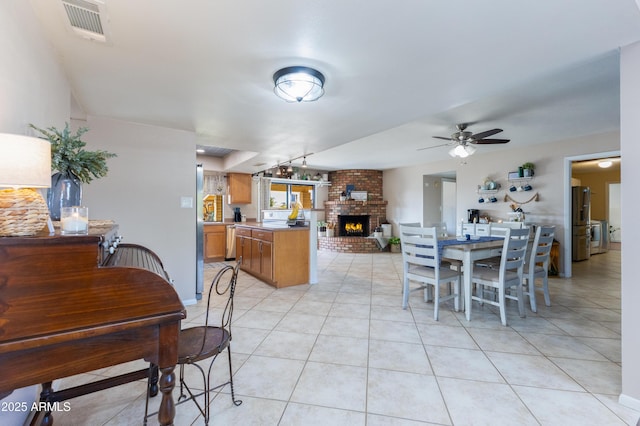 tiled dining space with a fireplace and ceiling fan