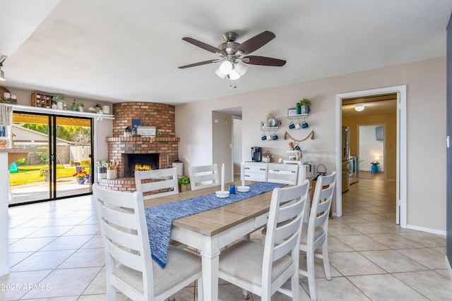 dining area featuring light tile patterned flooring, a brick fireplace, and ceiling fan