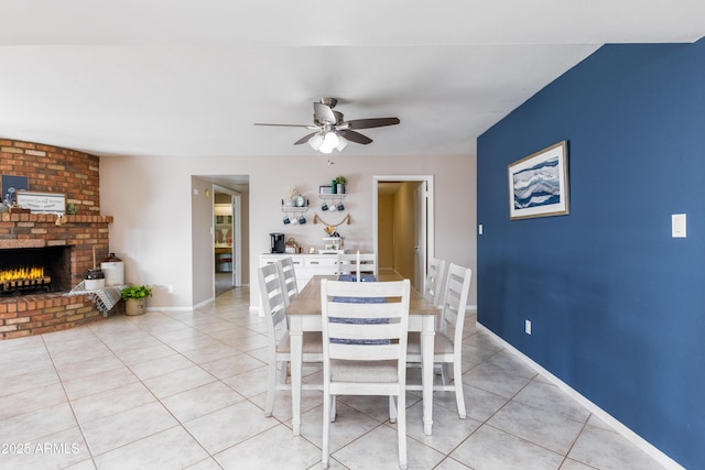 unfurnished dining area with a brick fireplace, ceiling fan, and light tile patterned flooring