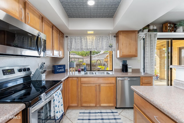 kitchen with a raised ceiling, appliances with stainless steel finishes, sink, and light tile patterned floors