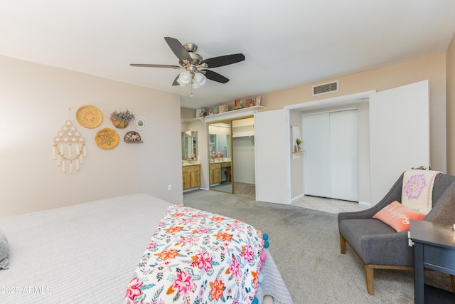 carpeted bedroom featuring ceiling fan, ensuite bathroom, and two closets